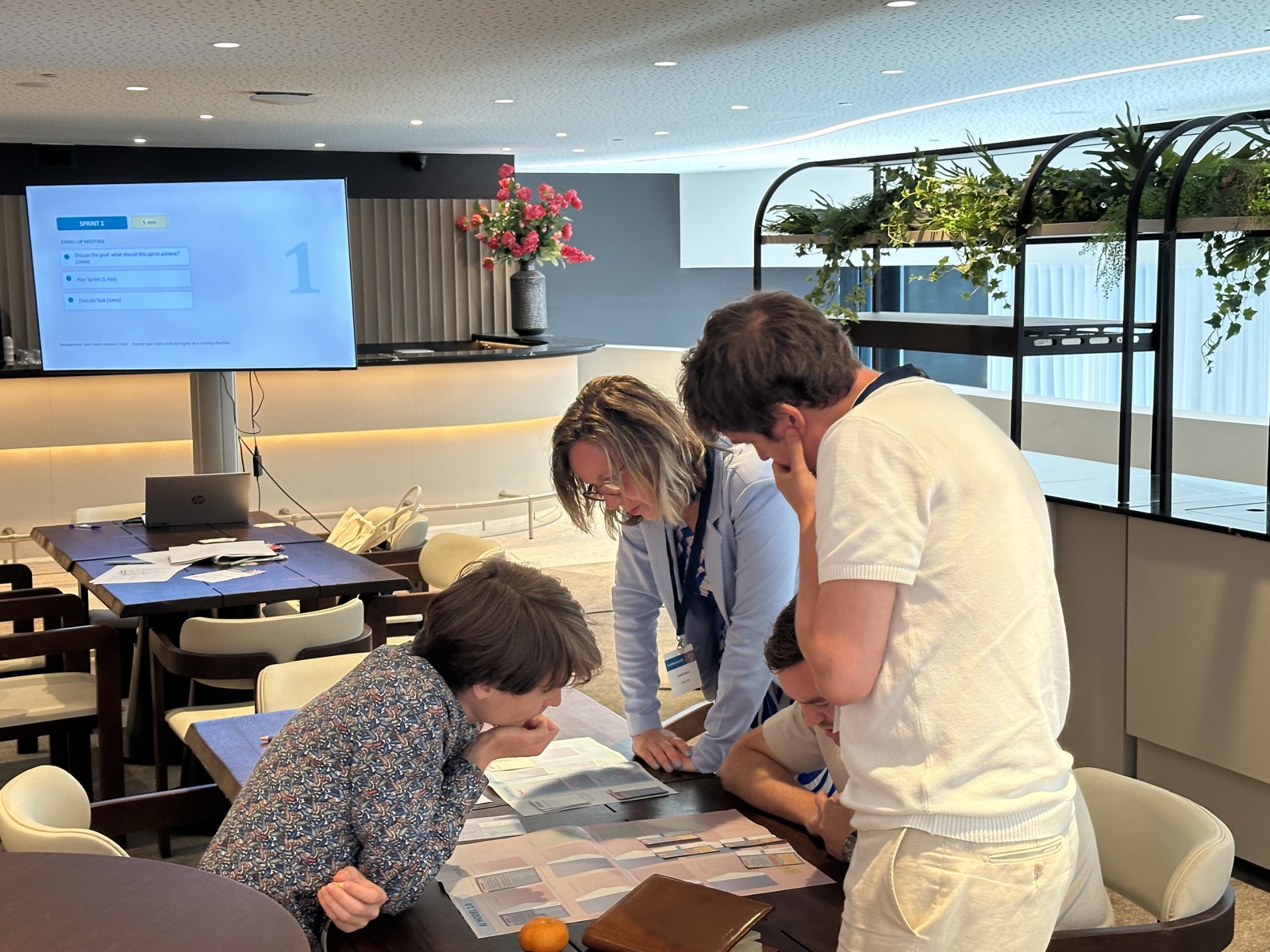Four people leaning over a table, reading the game's boards and cards together.
