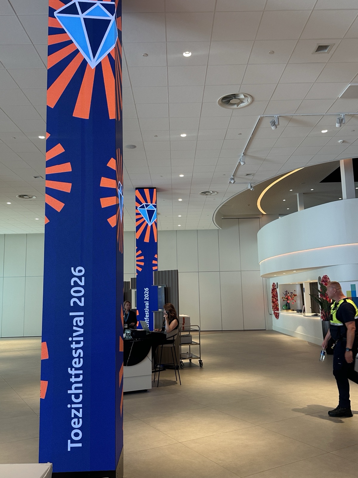 Tall Toezichtfestival 2026 banners in the venue foyer, with the registration desk behind them.